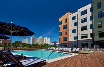A pool with chairs and umbrellas next to a building